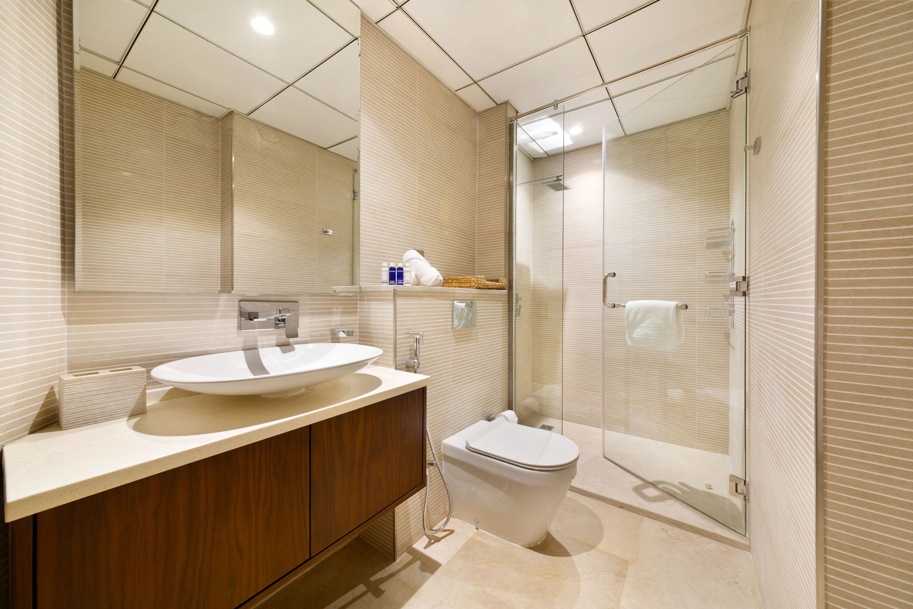 A modern bathroom with a large mirror, a sink, and a toilet.