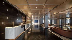 A modern lobby with a reception desk, seating area, and a large wall with a blue artwork. - Wyndham Grand Plaza Royale Yujia Anhua (Yiyang)