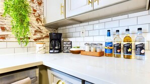 Une cuisine avec des armoires blanches, une machine à café et divers condiments disposés sur le comptoir.