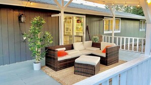 Un espace extérieur aménagé, abrité et doté de mobilier en osier et d’une plante en pot.