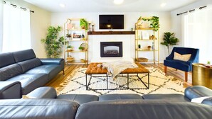 Un salon avec une cheminée, des canapés, une table basse et des étagères décoratives.