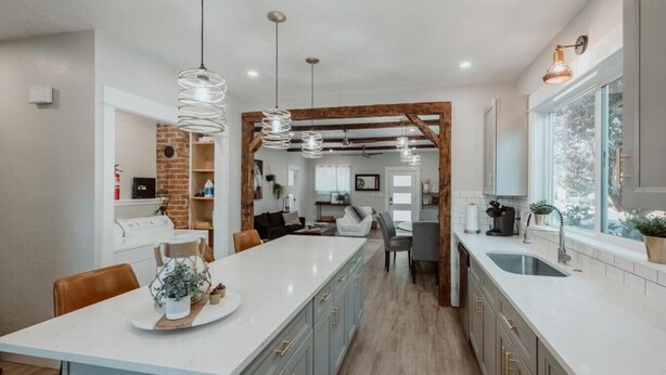 Une cuisine moderne dotée d’un îlot central, de luminaires suspendus et d’un mur en briques au style rustique.