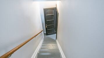A staircase with a wooden handrail leading to a dark door at the top.