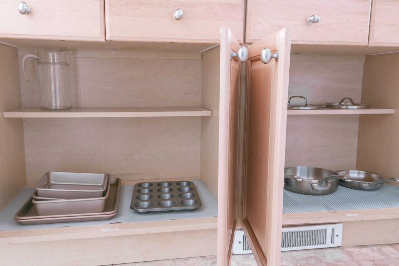 Une petite cuisine équipée d’un four à micro-ondes, d’une bouilloire, d’un moule à muffins et de deux bols en métal, le tout posé sur le plan de travail.