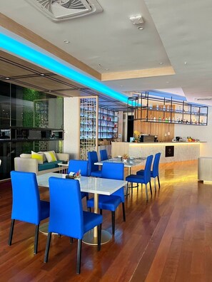 A modern interior with a dining area, bar, and seating with a view of the outdoors.