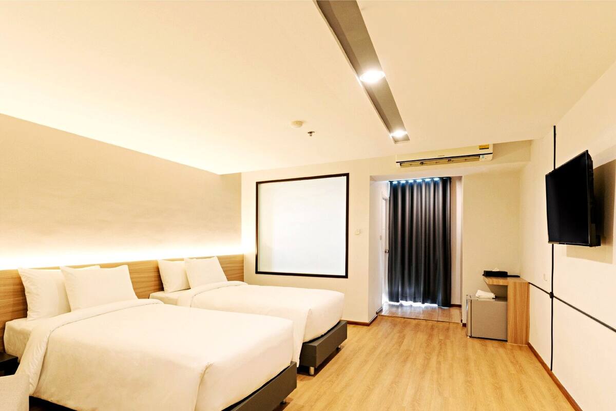 Een hotelkamer met twee bedden, een televisie, een bureau en een kleine kitchenette.