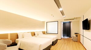 Habitación de hotel con dos camas, televisión, escritorio y kitchenette.
