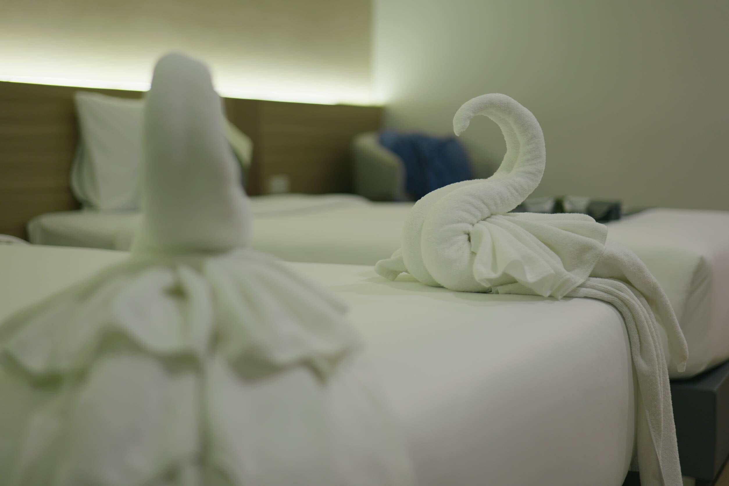 Neatly made white towels on hotel beds.