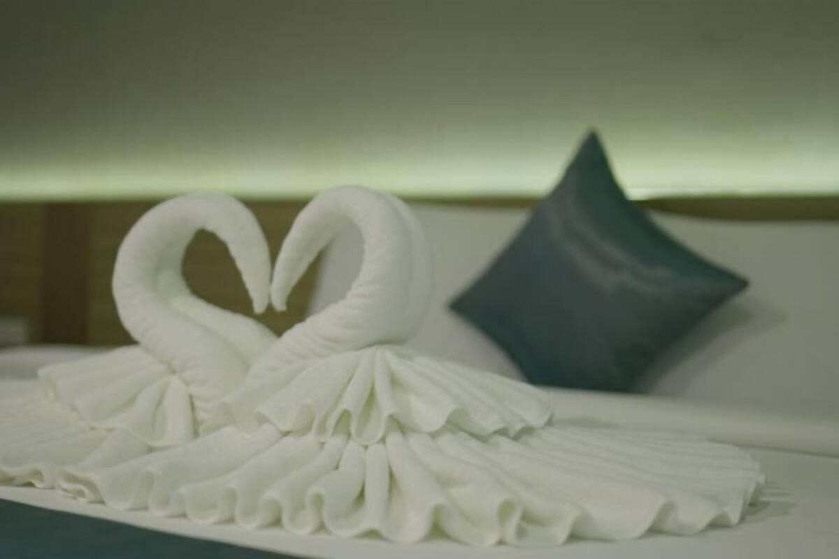 Een bed met een wit, zwaanvormig kussen en een hartvormig kussen.
