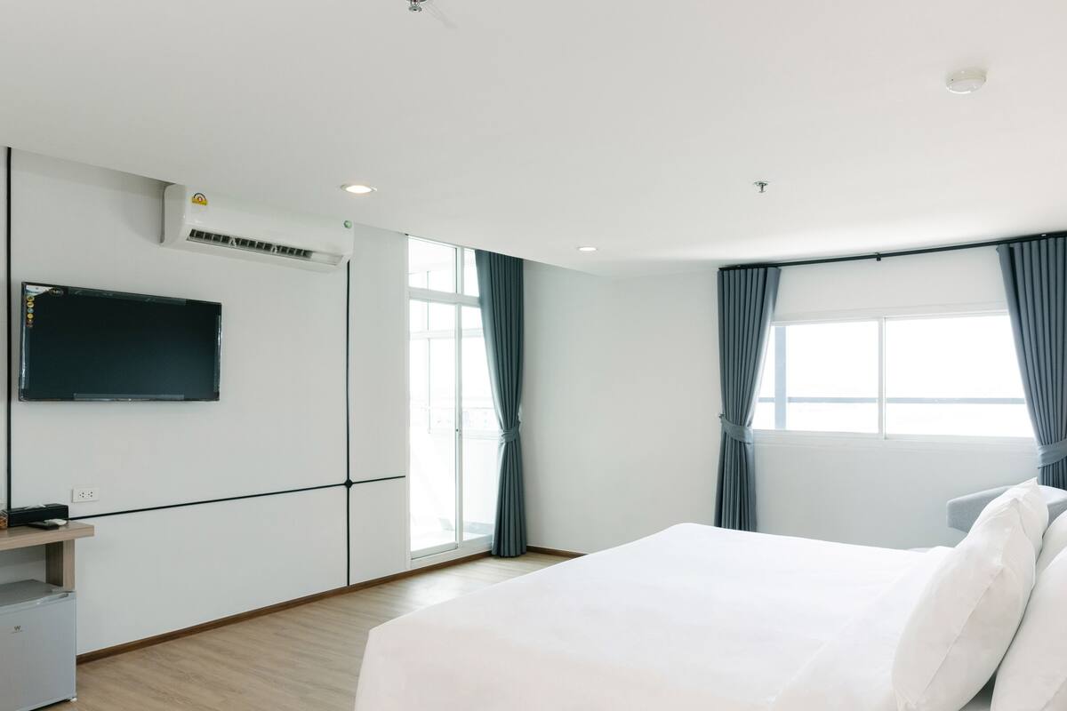 Een moderne hotelkamer met een groot bed, een flatscreen televisie aan de muur en een klein bureau met een computer en een waterfles.