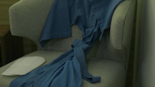 Une chaise recouverte d’un tissu bleu, placée contre un mur orné d’un panneau de bois.