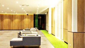 Un hall d’hôtel moderne doté d’un espace salon, d’une moquette verte et de lambris en bois.