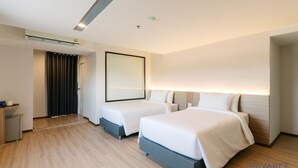 Une chambre d’hôtel moderne avec deux lits, un petit bureau et un miroir.