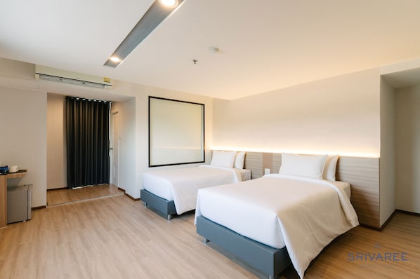 Una habitación de hotel moderna con dos camas, un escritorio pequeño y un espejo.