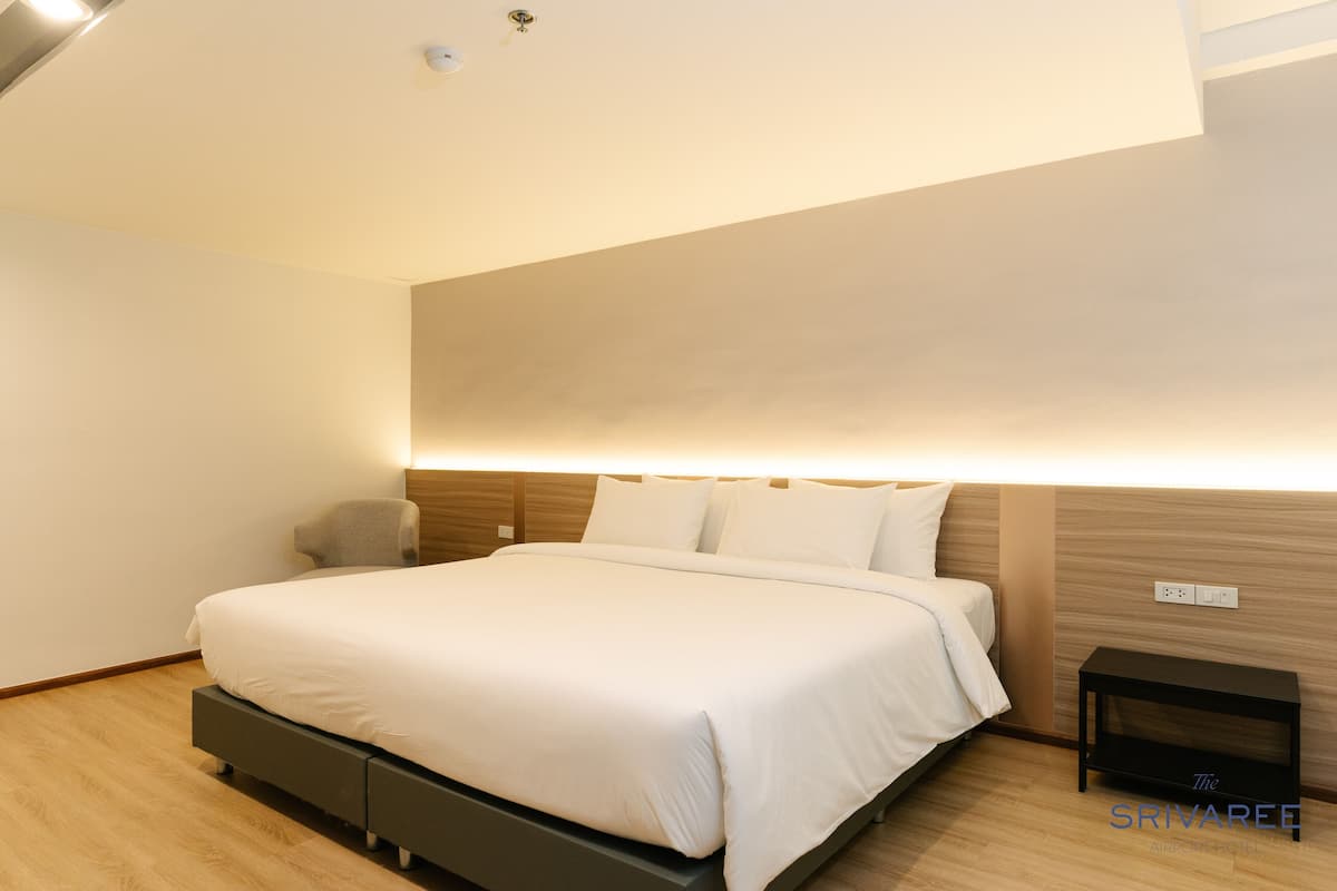 Een moderne hotelkamer met een groot bed, een nachtkastje en een wandlamp.
