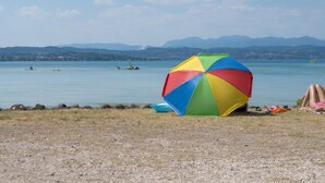 Une plage avec un parasol coloré et une côte rocheuse.