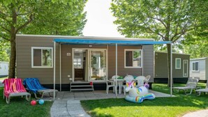 A mobile home with a covered patio, outdoor seating, and a lawn. - Garda Family Plus by Interhome (Desenzano)