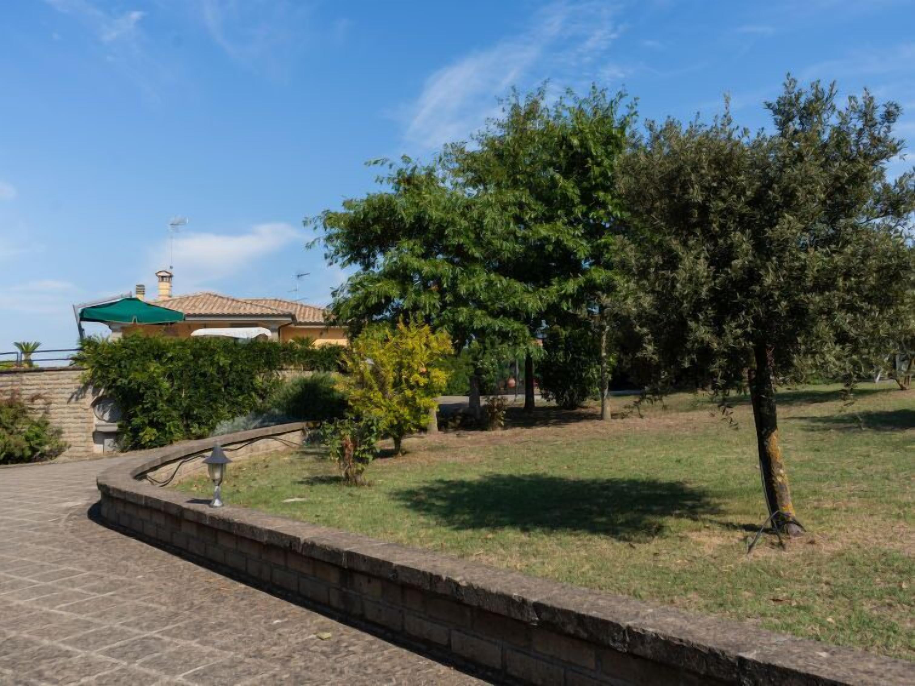A paved pathway leading to a building with a green roof and a chimney.