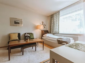 A cozy hotel room with a bed, a sofa, a small table, and a lamp.