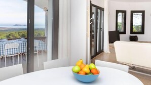 A modern room with a large window offering a scenic view, a dining area with a table and chairs, and a white sofa. - Can Delmas by Interhome (Pals)