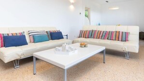 A modern living room with two white sofas, colorful striped cushions, a white coffee table, and a small side table. - Can Delmas by Interhome (Pals)