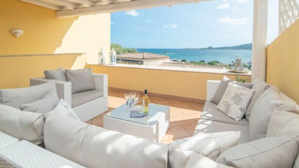 A balcony with white furniture, a glass coffee table, and a view of the sea. - Le Bijou by Interhome (Cannigione)
