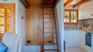 A wooden interior with a central staircase, white cabinets, and a kitchen area with a fruit basket.