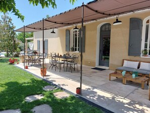 Un espace extérieur aménagé, abrité et doté d’une table et de chaises, d’un canapé et d’une plante en pot.