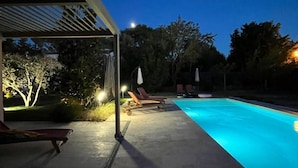 A swimming pool with lounge chairs and a covered area with lights. - Villa Art-Déco, 5 mn walk from the city center of Saint-Rémy- Pool, Clim - 4ps (Saint-Rémy-de-Provence)