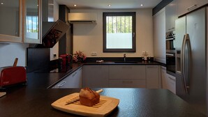 A modern kitchen with a large island, stainless steel appliances, and a window providing natural light. - Villa Art-Déco, 5 mn walk from the city center of Saint-Rémy- Pool, Clim - 4ps (Saint-Rémy-de-Provence)