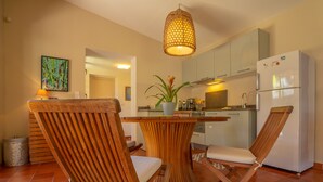 A modern kitchen with white cabinets, a built-in refrigerator, and a dining area with wooden chairs and a central table. - ST GILLES, CHARMING HOUSE, seaside, Coral villa, lagoon, 4 **** (Saint Paul)