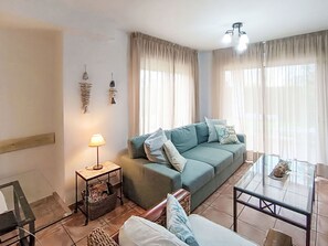 En stue med sofa, sofabord, lampe og lille natbord.