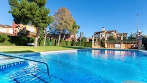 A swimming pool with clear blue water, surrounded by a well-maintained lawn and a fence.