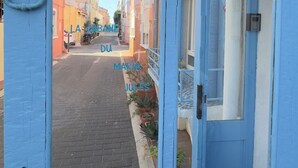 A blue door with a lion head knocker, leading to a narrow street with buildings. - SETE LA CABANE DU MARIN JULES (Sète)