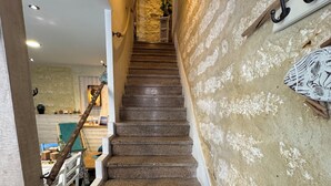 A staircase with a textured wall on the right and a kitchen area visible at the top. - SETE LA CABANE DU MARIN JULES (Sète)