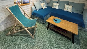 A cozy living room with a blue sofa, a wooden coffee table, and a teal patterned chair.