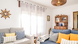 Un salón con un sofá gris, un sofá azul y un mueble de madera con puertas de cristal.