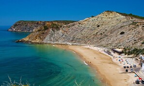 A coastal beach with clear turquoise waters, a sandy shore, and a rocky cliff. - Scilla White Villa, Vila do Bispo, Algarve (Vila do Bispo)