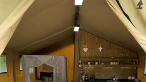 Un alojamiento en tienda de campaña acogedor, con cama, sofá, mesa de comedor y sillas.