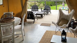 Un espacio al aire libre con carpas, una mesa, sillas, un farol y vistas a un jardín y una piscina.