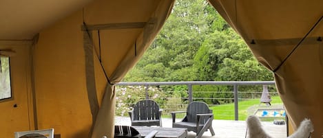 Ein überdachter Außenbereich mit Tisch und Stühlen, einer Laterne und Blick auf Garten und Pool.