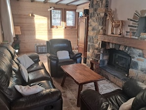 A cozy living room with a stone fireplace, leather sofas, and a wooden coffee table.