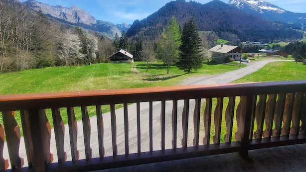 A mountain landscape with a wooden deck overlooking a rural area, featuring houses and a road. - Quiet chalet in Abondance, 4 bedrooms, fireplace (Abondance)