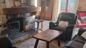 A cozy living room with a stone fireplace, leather sofas, and a wooden coffee table. - Quiet chalet in Abondance, 4 bedrooms, fireplace (Abondance)