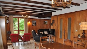 A wooden-paneled room with a dining table, chairs, a sofa, and a television. - Quiet chalet in Abondance, 4 bedrooms, fireplace (Abondance)