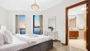 Camera d'albergo moderna con un grande letto, una scrivania, uno specchio e vista sul mare.