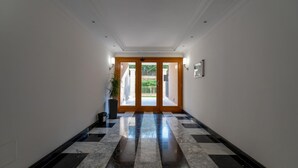 A hallway with a checkered marble floor, a wooden door with glass panels, and a potted plant. - Casa Titty in Roma With 1 Bedrooms and 1 Bathrooms (Rome)