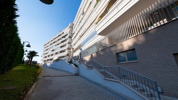 A multi-story hotel with a modern design, featuring balconies with plants, a brick facade, and a paved pathway leading to the entrance. - Casa Titty in Roma With 1 Bedrooms and 1 Bathrooms (Rome)
