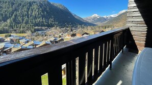 A wooden balcony with a view of a mountain village and snow-capped peaks. - Spacious studio near center and lift with parking (Châtel)