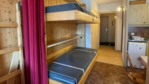 A compact room with a bunk bed, a small kitchenette, and a wooden floor. - Spacious studio near center and lift with parking (Châtel)